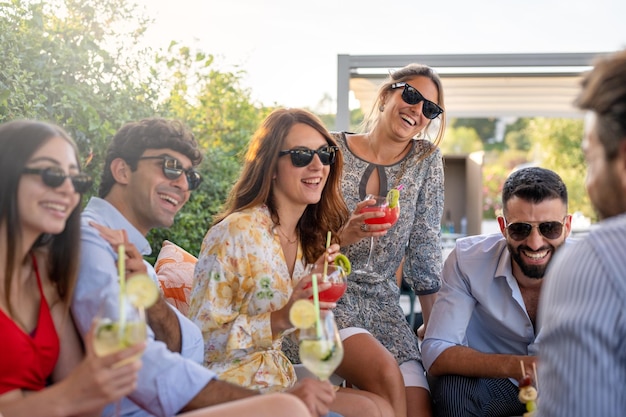 Group of fashionable people drinking cocktails young couples\
laughing and having fun during an aperitif happy hour time for\
young friends generation z leisure