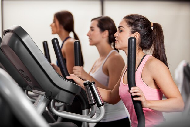 Group of female friends doing some cardio in an elliptical trainer in a gym