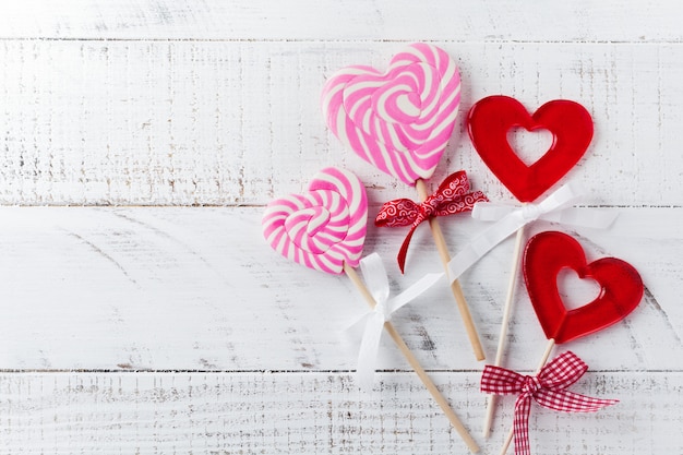 Group of festive various candies in form of heart on white wooden background