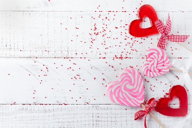 Group of festive various candies in form of heart on white wooden background