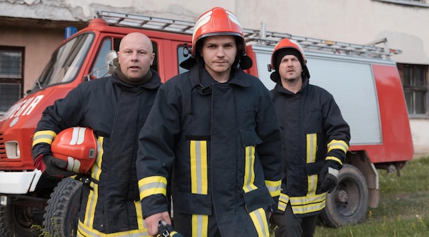 Группа пожарных уверенно стоит после хорошо проведенной спасательной операции. Пожарные готовы к аварийной службе. Фото высокого качества