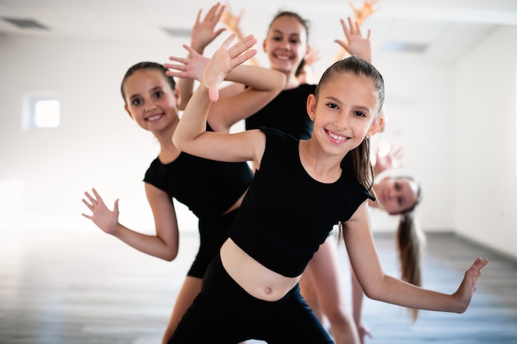 Photo group of fit happy children exercising ballet in studio together