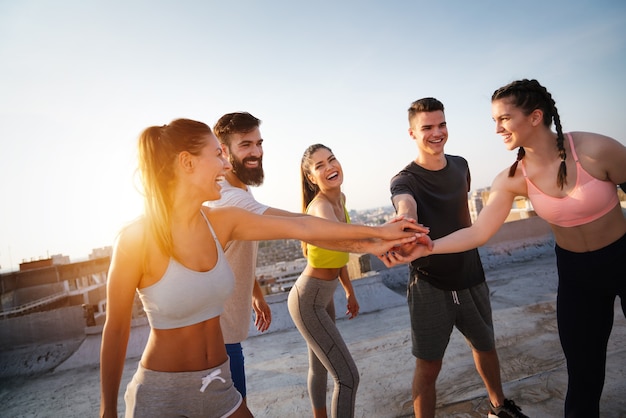 Photo group of fit healthy friends, people exercising together outdoor on rooftop