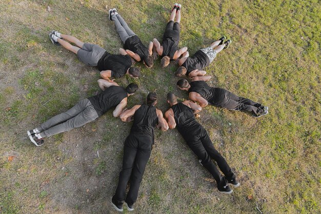 Photo group of fitness people doing push ups in park.