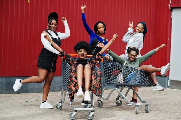 쇼핑 카트를 들고 야외에서 함께 즐거운 시간을 보내는 5명의 아프리카계 미국인 여성 그룹