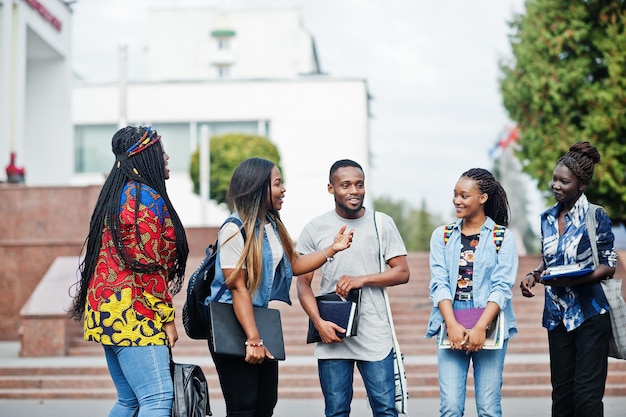 Un gruppo di cinque studenti universitari africani che trascorrono del tempo insieme nel campus del cortile dell'università amici afro neri che studiano il tema dell'istruzione