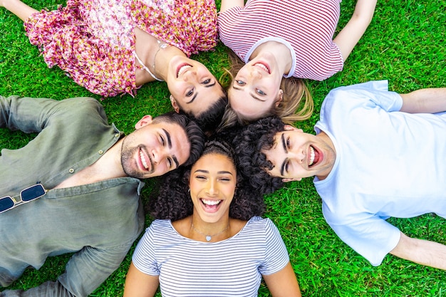 group of five happy young diverse multiracial gen z friends lying in circle head to head 