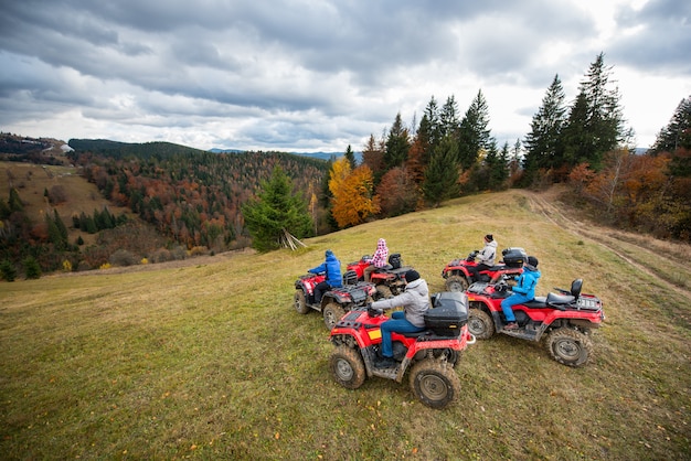Group of five people driving quad bikes on the hillside