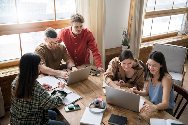 Group of five using laptops and notebooks for learning in a study session