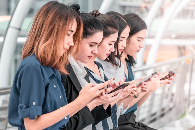 Group of Five young woman standing  using digital tablet cellphone in city