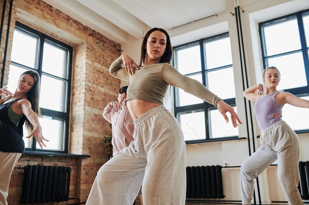 Group of flexible teenagers in activewear performing voge dance in loft studio