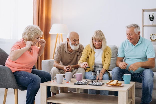 Photo group of four cheerful senior people playing bingo game in nursing home