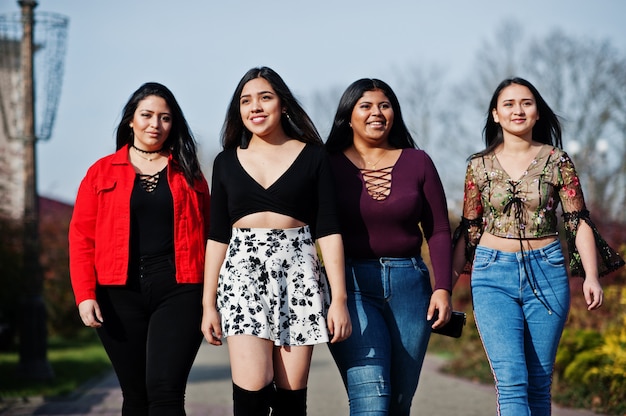 Group of four happy and pretty latino girls from Ecuador posed at street.