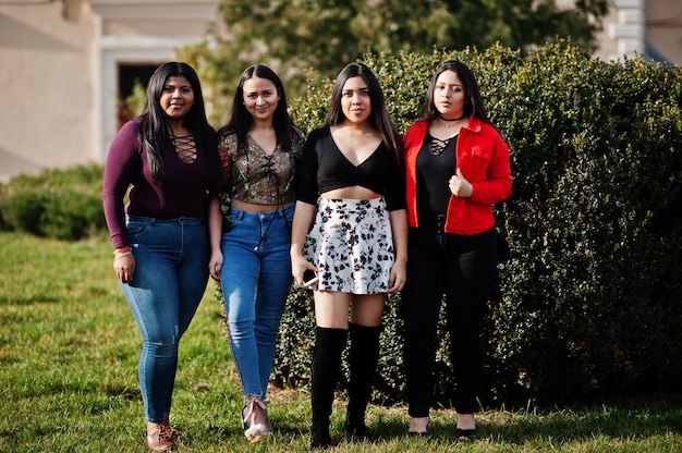 Group of four happy and pretty latino girls from Ecuador posed at street.