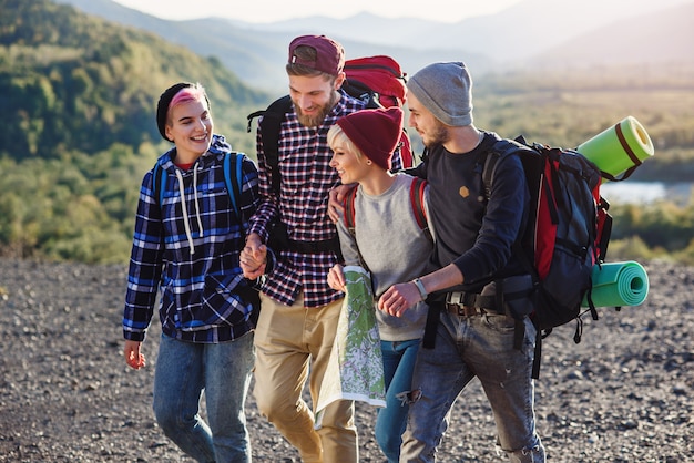 group of four happy travelers are walking with the map