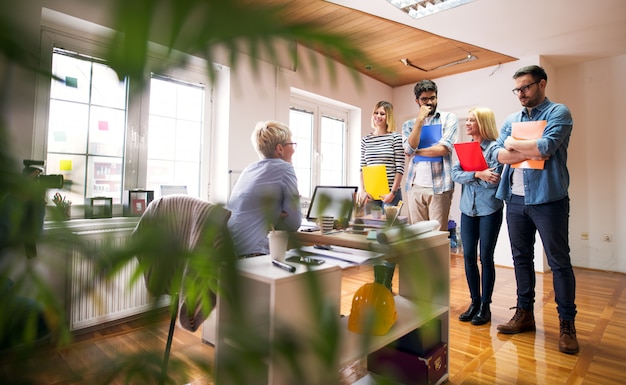 Group of four nervous engineers are at their job interview,  standing in front of their interviewers desk in a very bright office