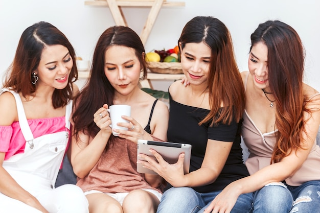 Group of four woman friends use digital tablet