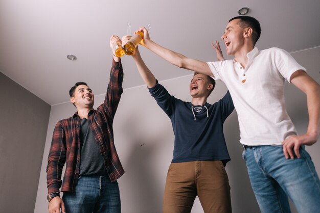 Gruppo di quattro giovani amici che tintinnano bottiglie di birra