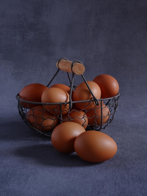 A group of fresh eggs in rustic iron basket and on grey base and background.