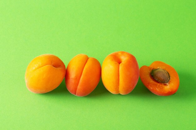 Group of fresh ripe apricots on bright green background