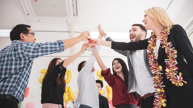 Group of friend celebrating holding flutes of champagne while dancing.