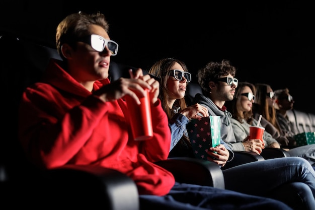 Группа друзей смотрит фильм в 3D очках Выборочный фокус в центре фото