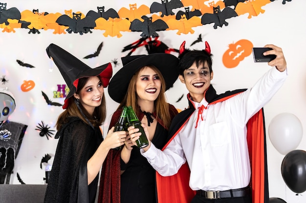 Group of friends asian young adult people celebrate a Halloween party. They wear Halloween costumes take selfie photographing. Halloween celebrate and international holiday concept.