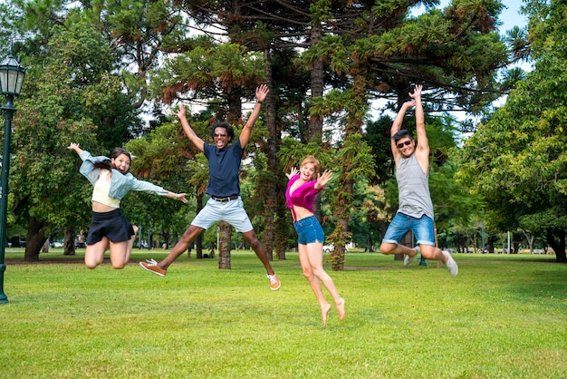 幸せで公園でジャンプしている友人のグループ