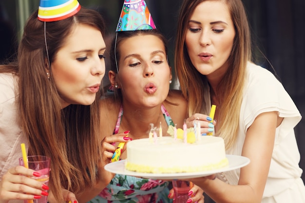 Gruppo di amici che soffiano candeline sulla torta di compleanno