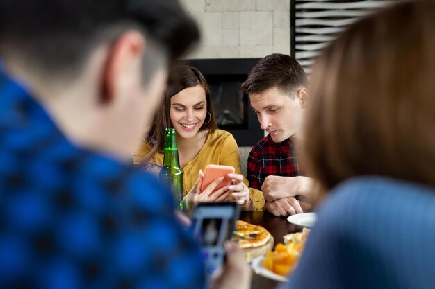 Group of friends in a cafe with pizza and beer having fun The girl shows the guy a funny photo