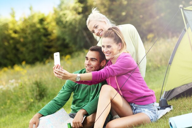 Gruppo di amici che si accampano nella foresta e si fanno selfie