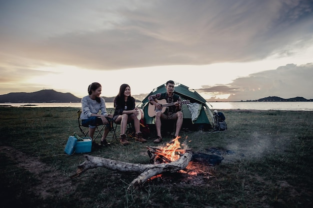 Group of friends camping.They are sitting around fire camp.