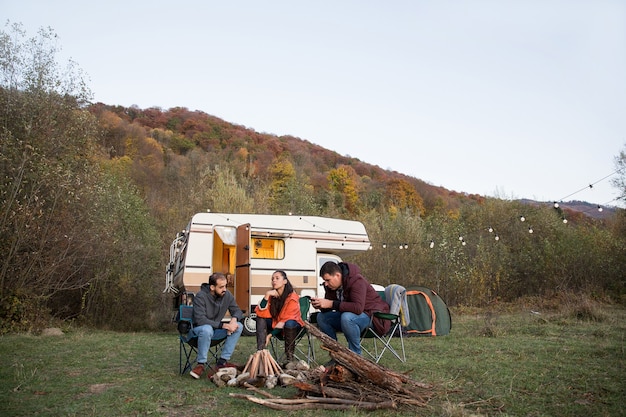 キャンプファイヤーを作るために夜を待ち望んでいる山で一緒にキャンプしている友人のグループ。レトロなキャンピングカー。