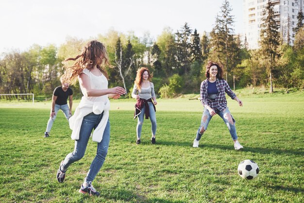 A group of friends in casual outfit play soccer in the open air. People have fun and have fun. Active rest and scenic sunset