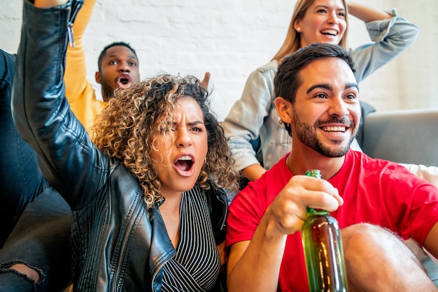 Group of friends celebrating and cheering while watching a match together. Friends concept.