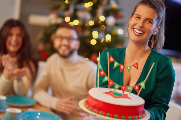 group of friends celebrating Christmas at home enjoying x-mass cake