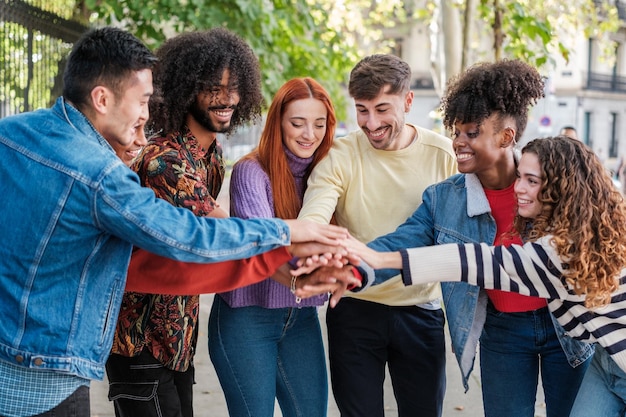 Group of friends celebrating and putting their hands together working as a team outdoors