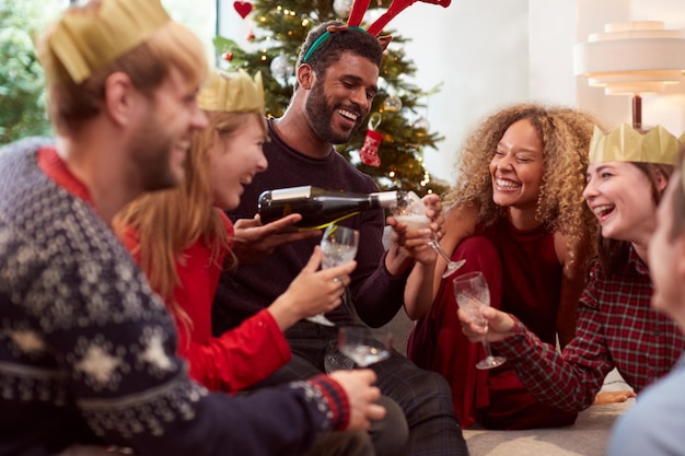 Gruppo di amici che festeggiano con champagne dopo aver gustato la cena di natale a casa