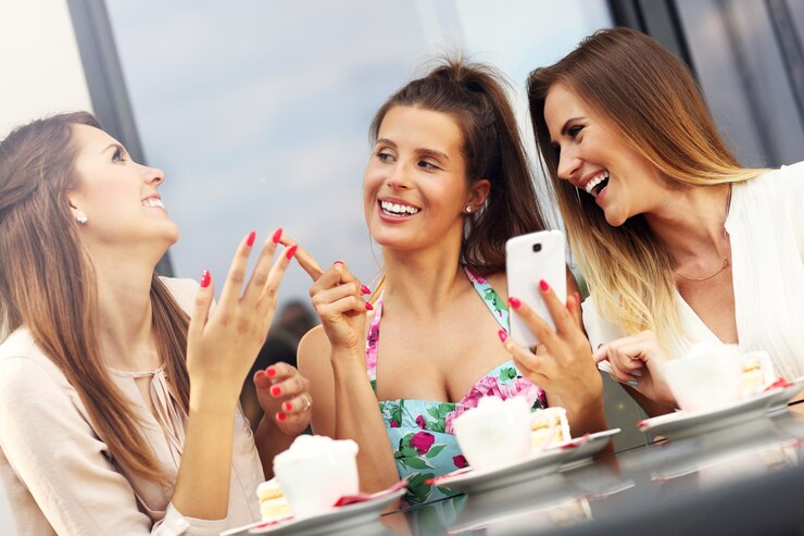 group of friends chatting in cafe and using smartphone