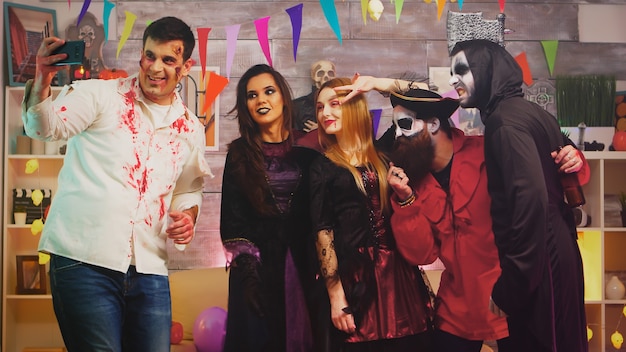 Group of friends in costumes taking a selfie at halloween party.