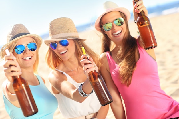 group of friends drinking beer on the beach