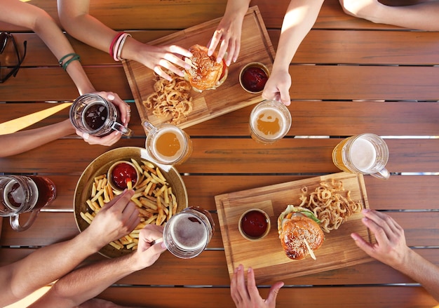 ビールを飲み、木製の背景に軽食を食べる友人のグループ
