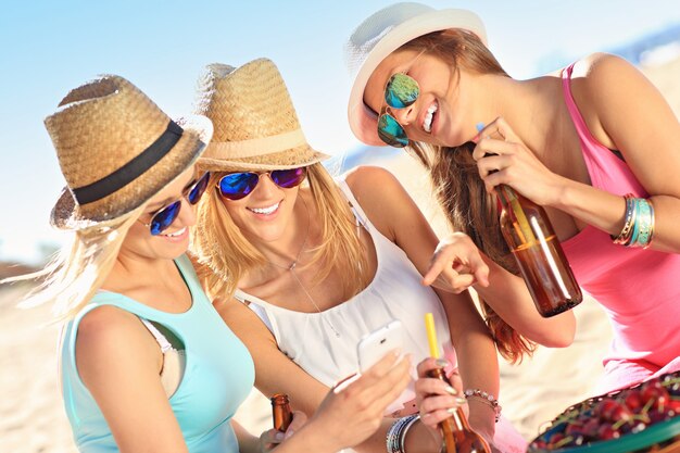 group of friends drinking beer and texting on the beach