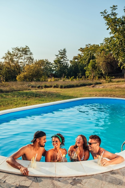 Group of friends drinking cocktails in a swimming pool