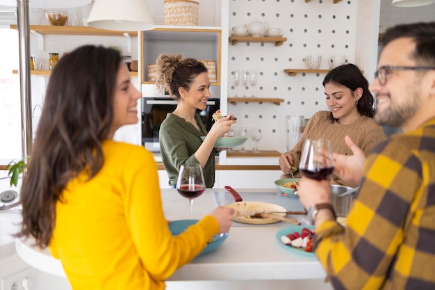 Group of friends eating pasta together in the kitchen