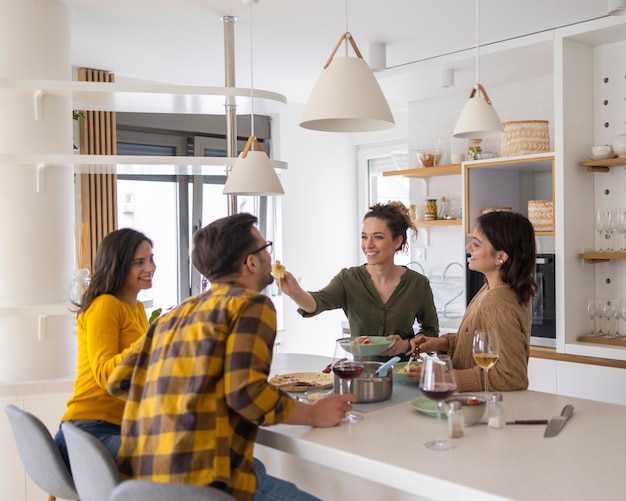 Group of friends eating pasta together in the kitchen