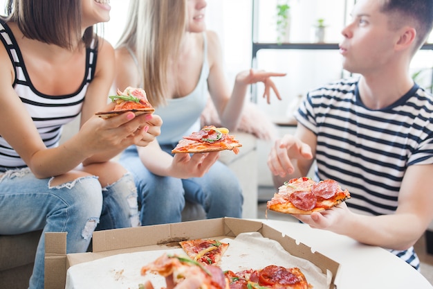 Group of friends eating pizza indoors