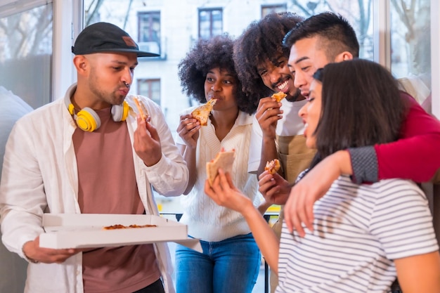 自宅のテラスでピザを食べる友人のグループ 昼食や夕食のライフスタイル 箱からおいしいピザを配布する