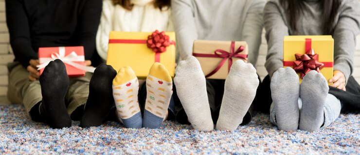 group of friends feet with socks holding gift boxes and sitting on carpet 