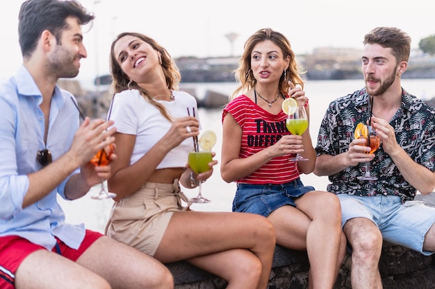 Un gruppo di amici si riunisce nel fine settimana al bar sul lungomare e si diverte a passare il tempo bevendo cocktail e chiacchierando insieme stile di vita giovanile e concetto di amicizia